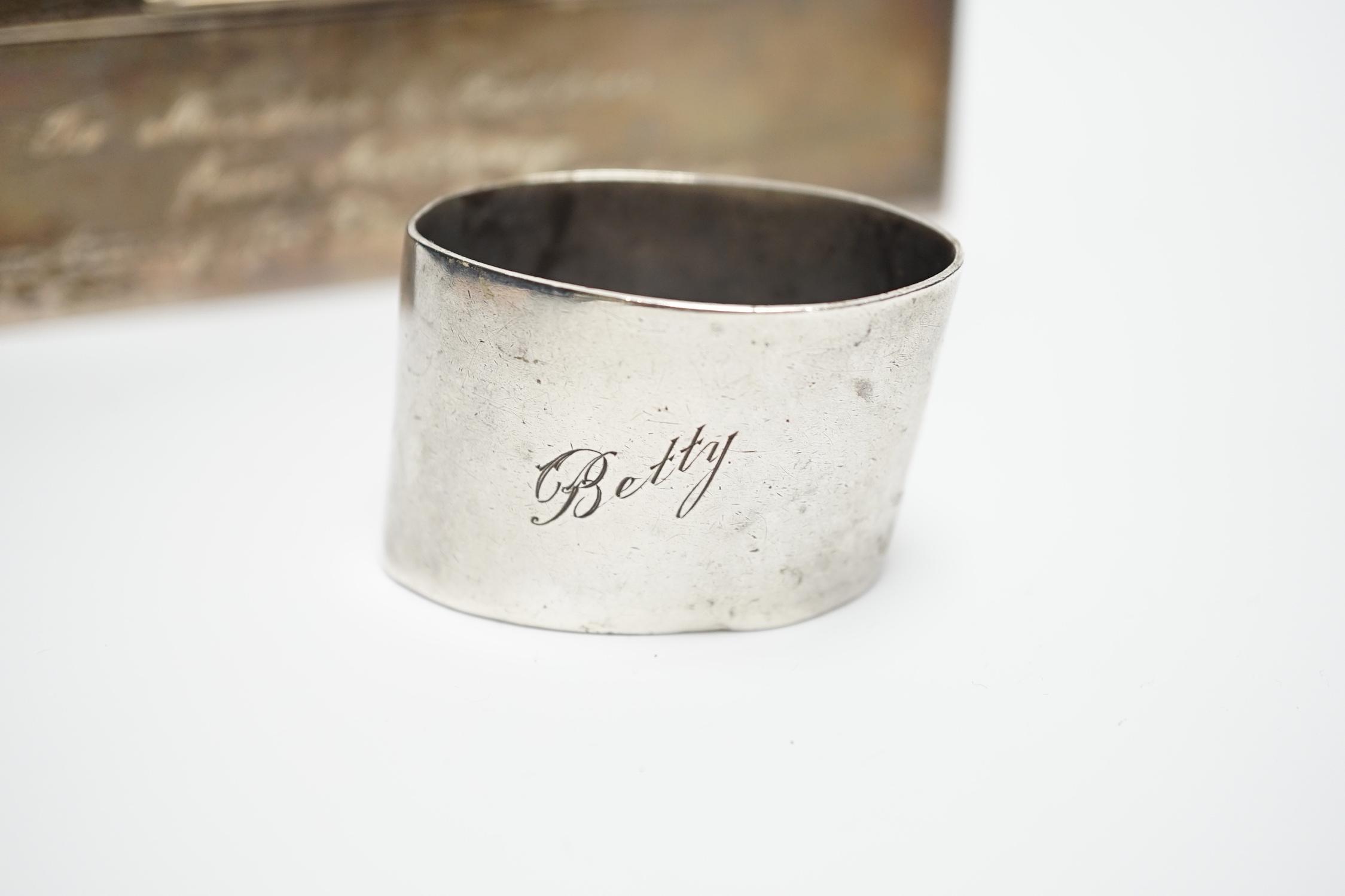 A modern part engine turned silver cigarette box, with engraved inscription, 16cm and a silver serviette ring.